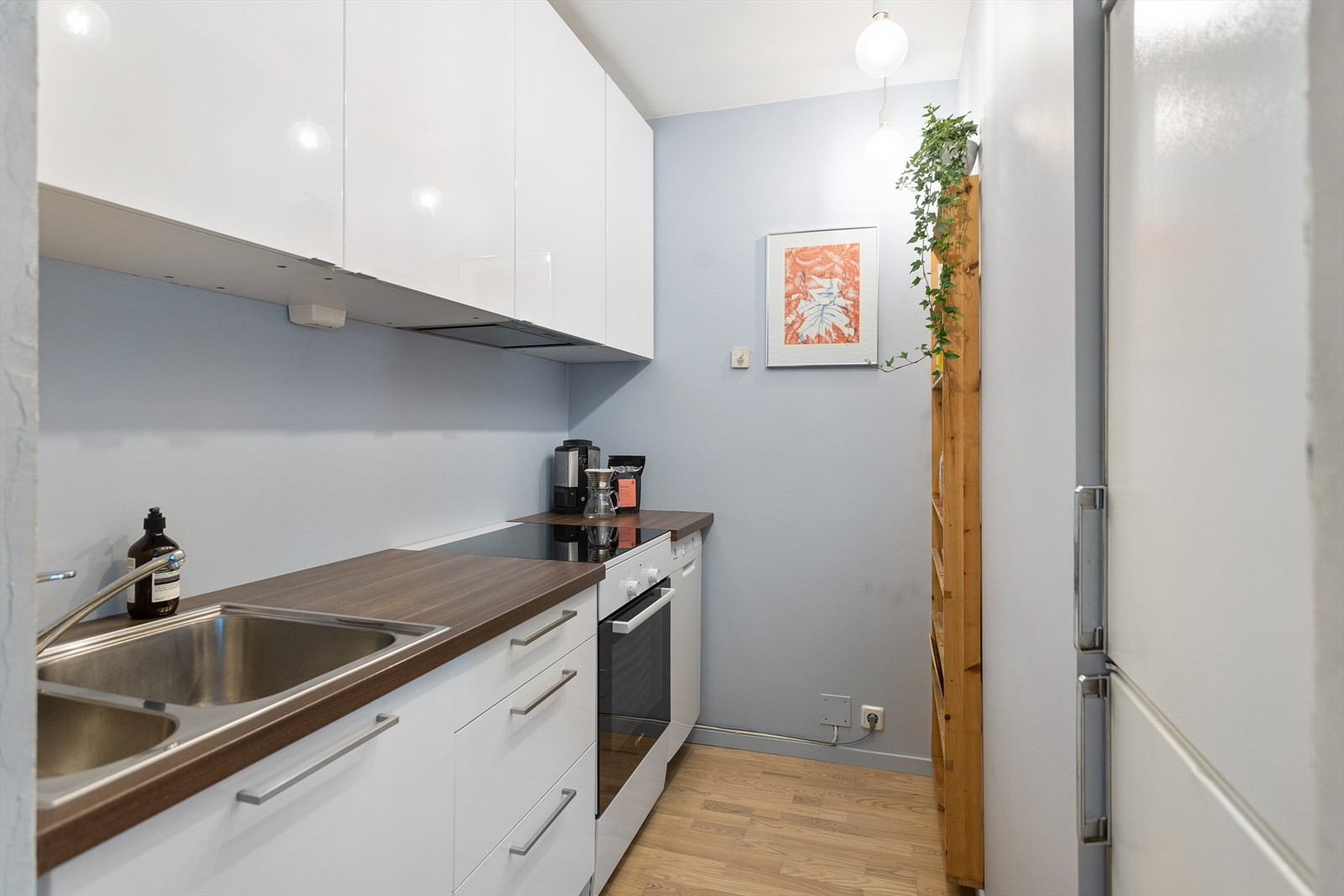 Kjøkkeninnredning fra 2012 med hvite glatte fronter og benkeplater i laminat. Frittstående hvitevarer med kjøleskap, komfyr og oppvaskmaskin følger med.